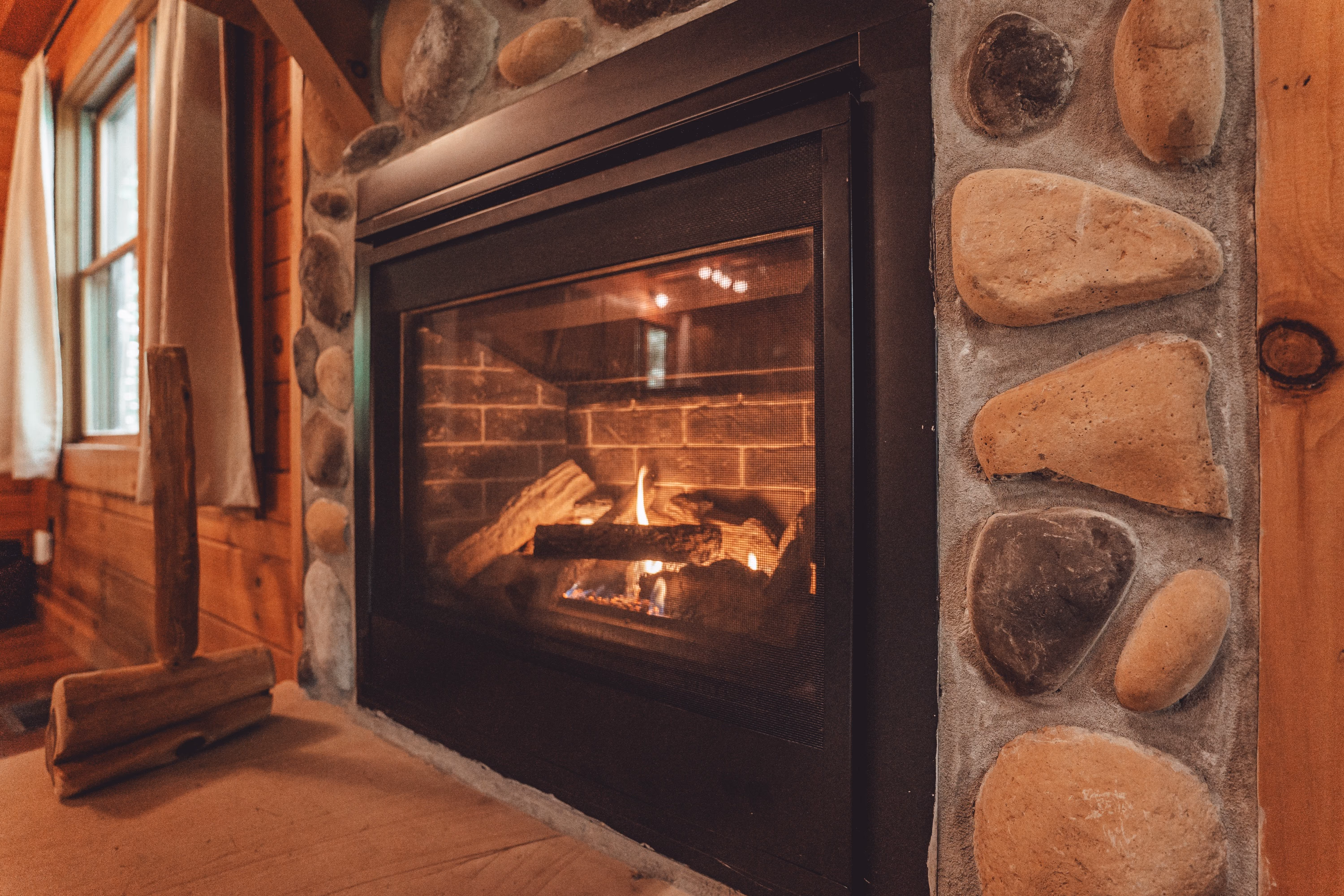 Flames in the gas fireplace framed by river stone