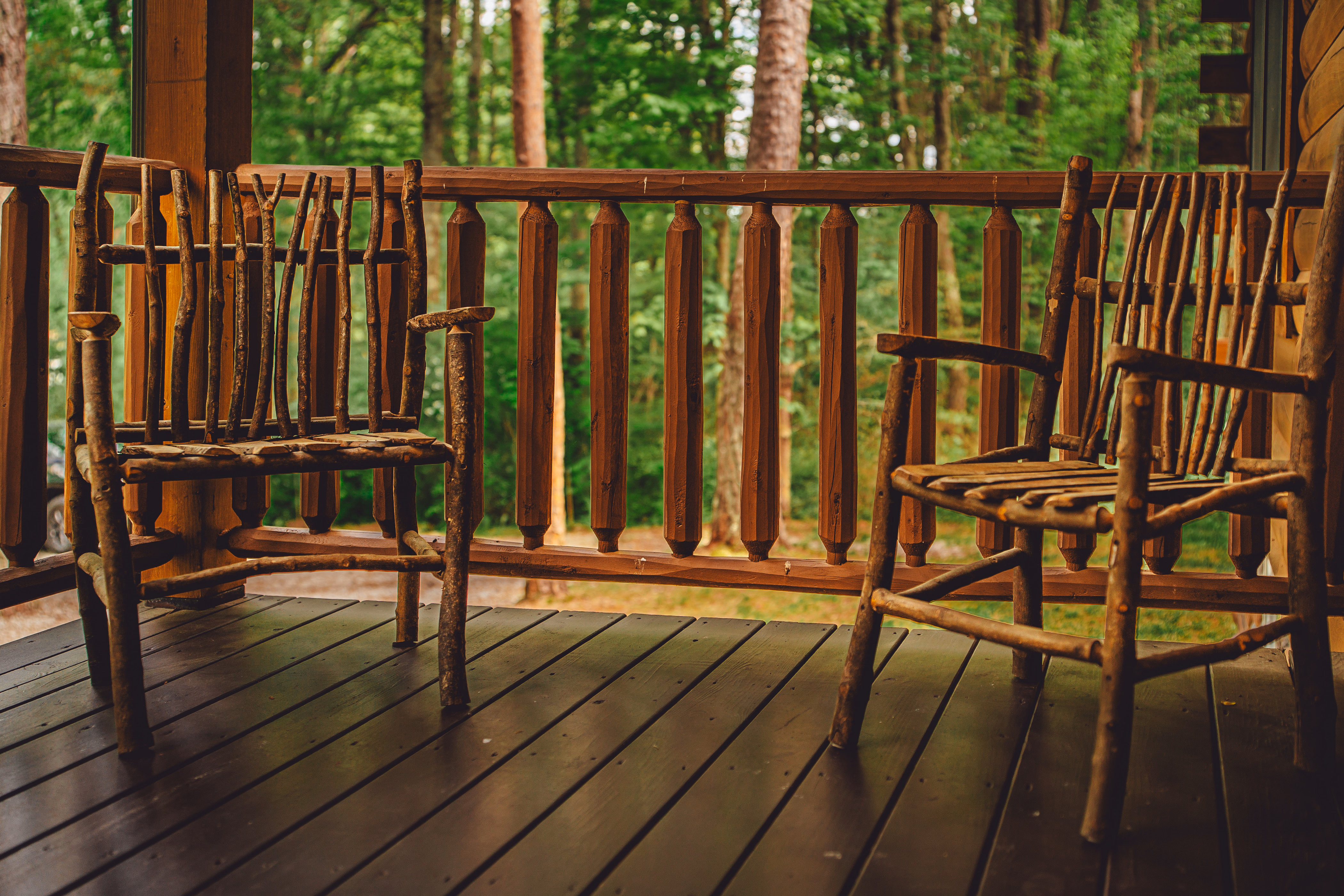 Two handmade wooden chairs on the front porch overlooking the forest