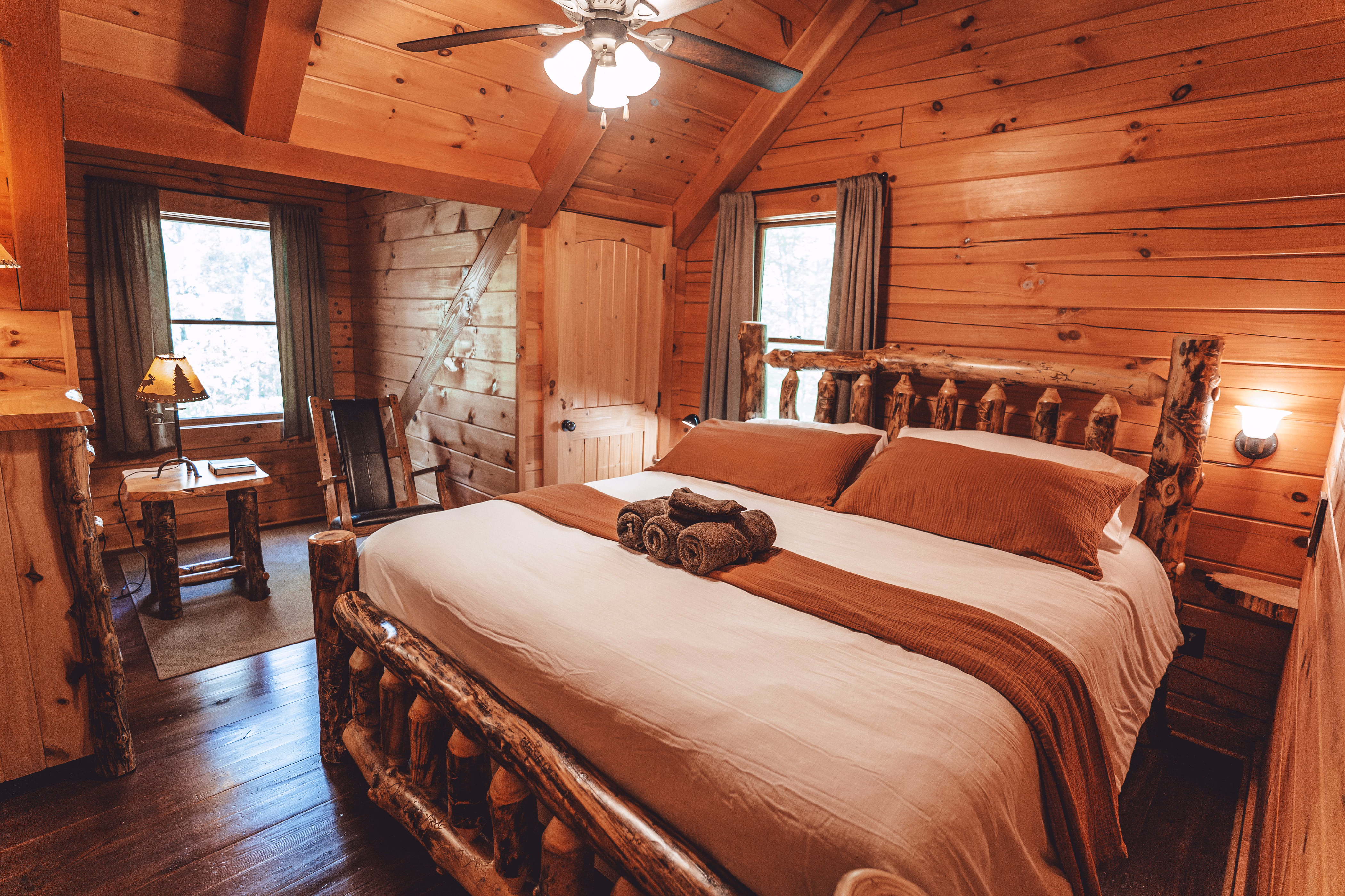 Bedroom with a king bed, vaulted timber ceiling, and reading chair