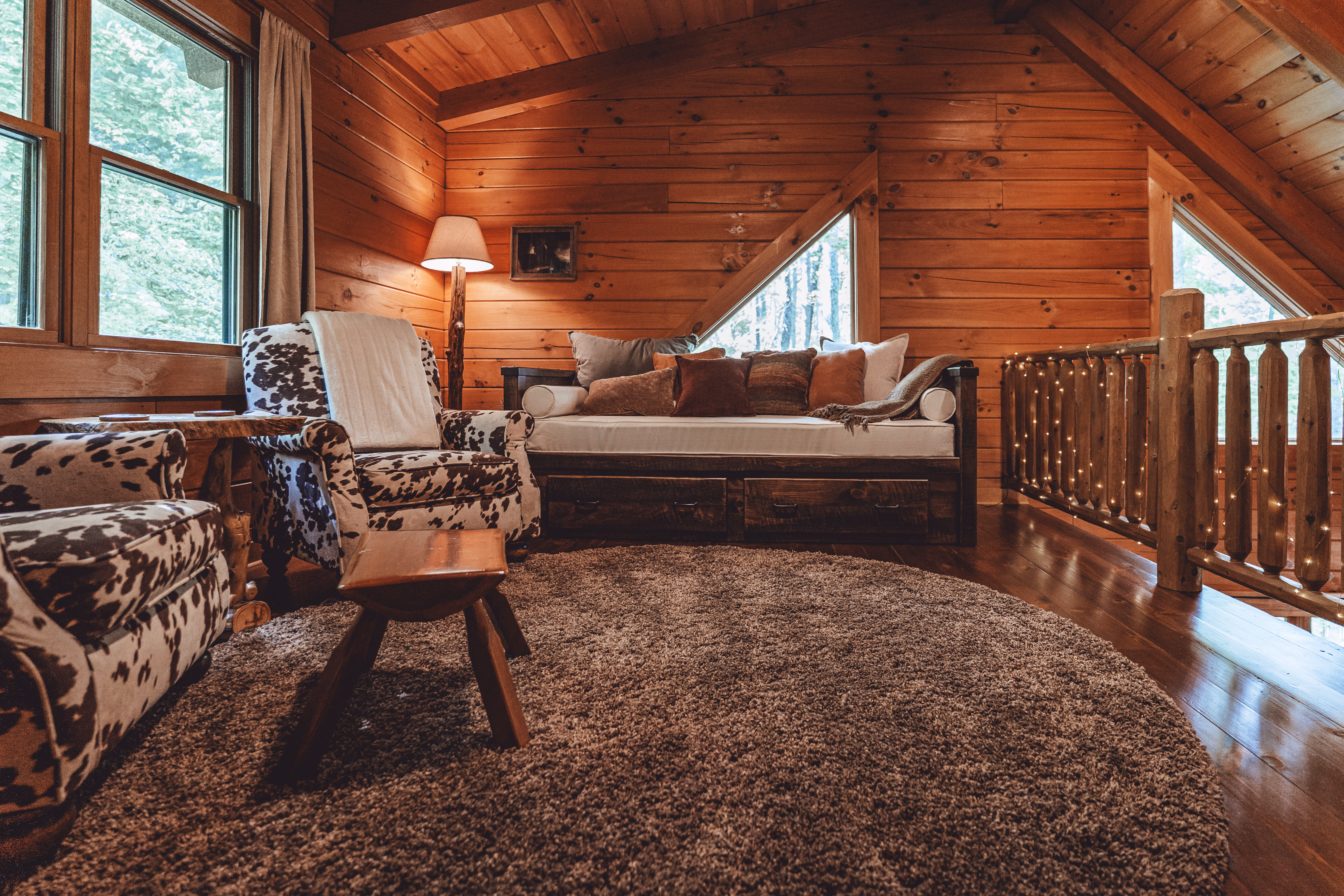 Open loft with a daybed, two armchairs, and woodland views