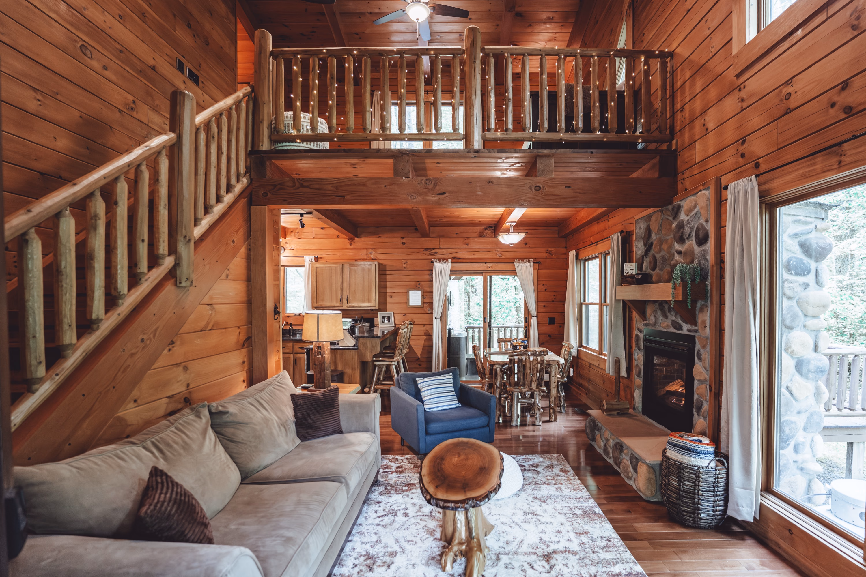 The living room with a sofa, armchairs, and the loft railing above